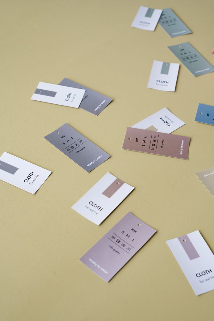 About Scattered clothing tags on a neutral background, showcasing colors and designs.