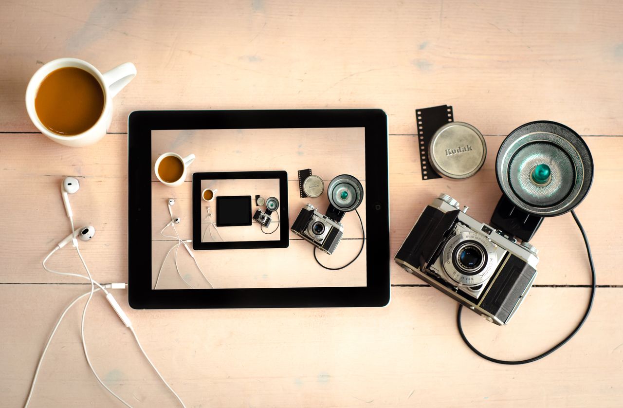 Services Flat lay of vintage camera, tablet, and coffee on a wooden desk.